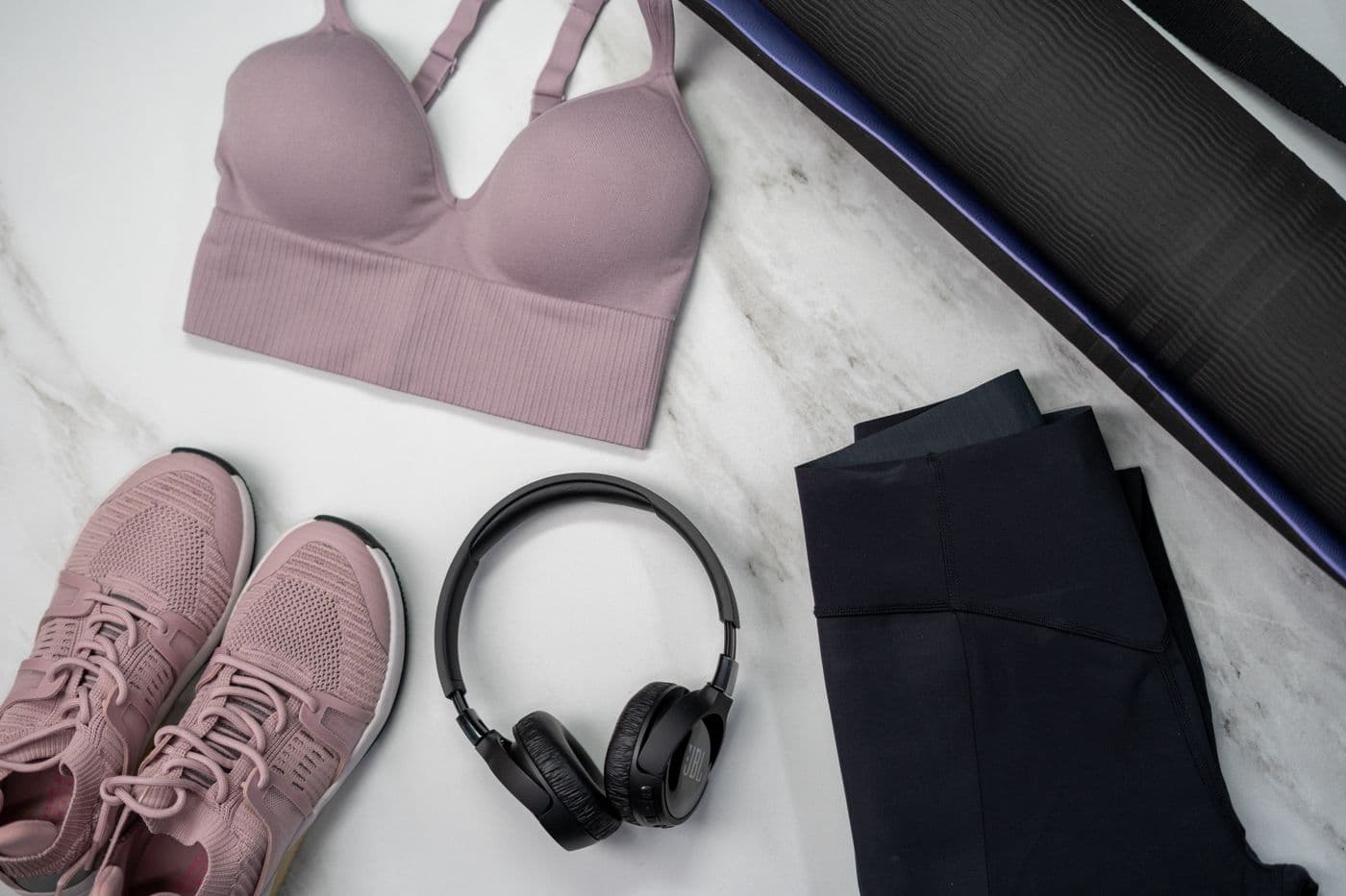 Flat lay of sports bra, leggings, sneakers and headphones