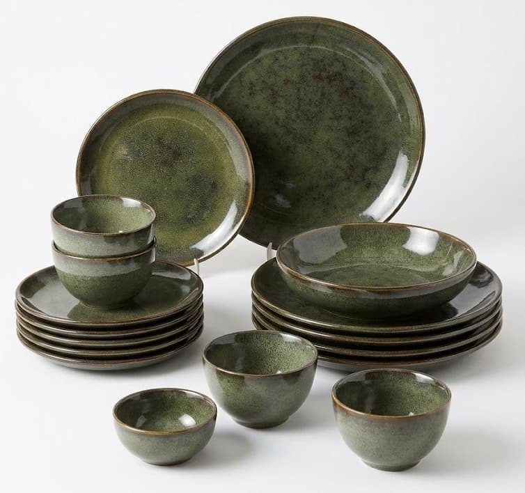 Green reactive glaze ceramic dinnerware set with plates and bowls on white background