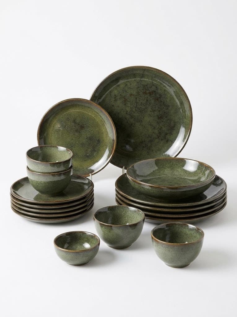 Green reactive glaze ceramic dinnerware set with plates and bowls on white background