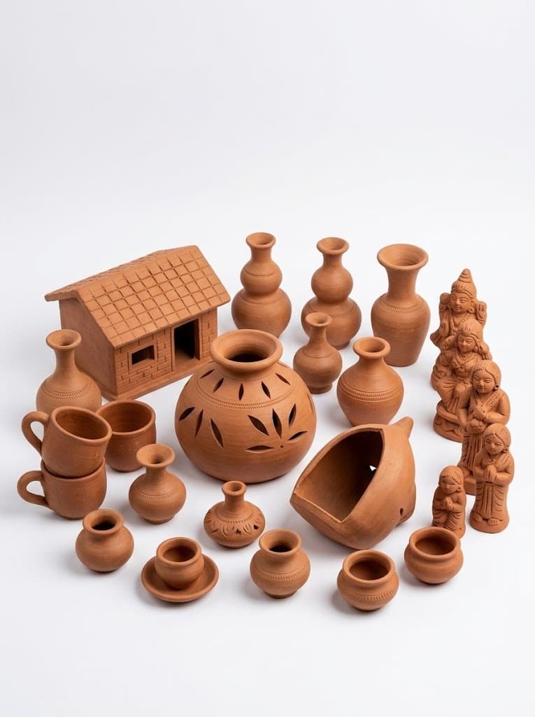 Terracotta pottery collection with hut model, vases, pots and figurines on white background