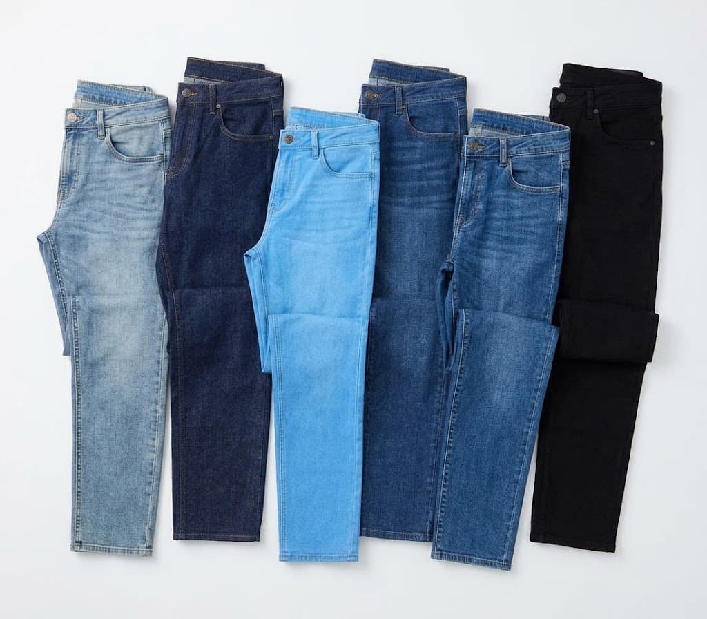 Six pairs of jeans laid in a row from light wash to black