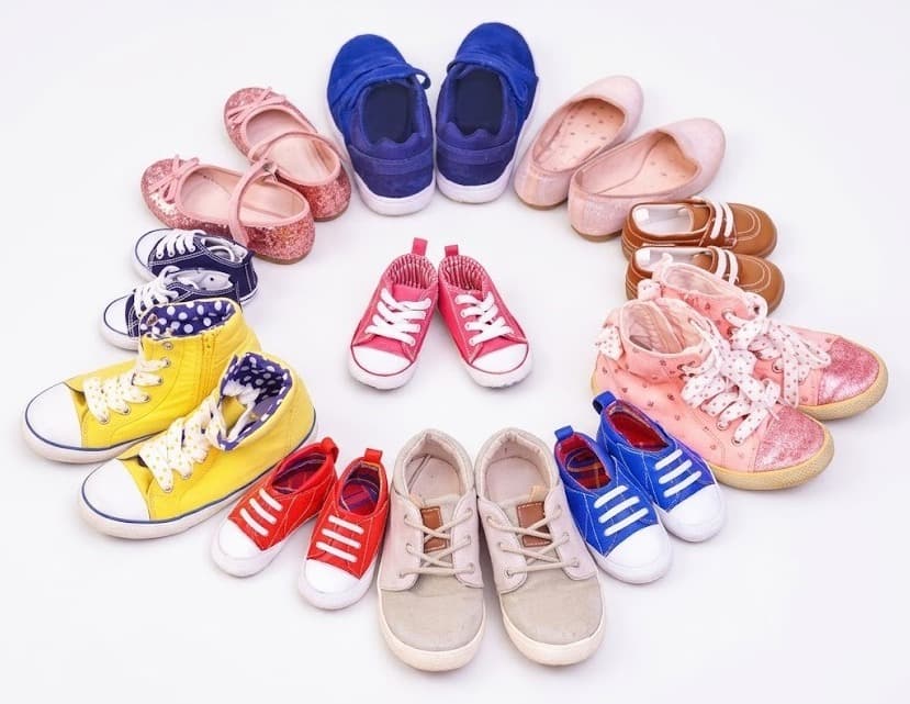 Kids' shoes arranged in a circle including sneakers, sandals and ballet flats