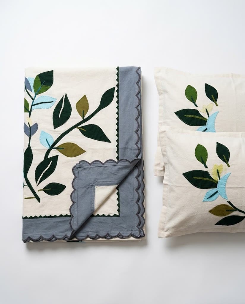 Quilted table runner and cushions with green and blue leaf appliqué on natural linen
