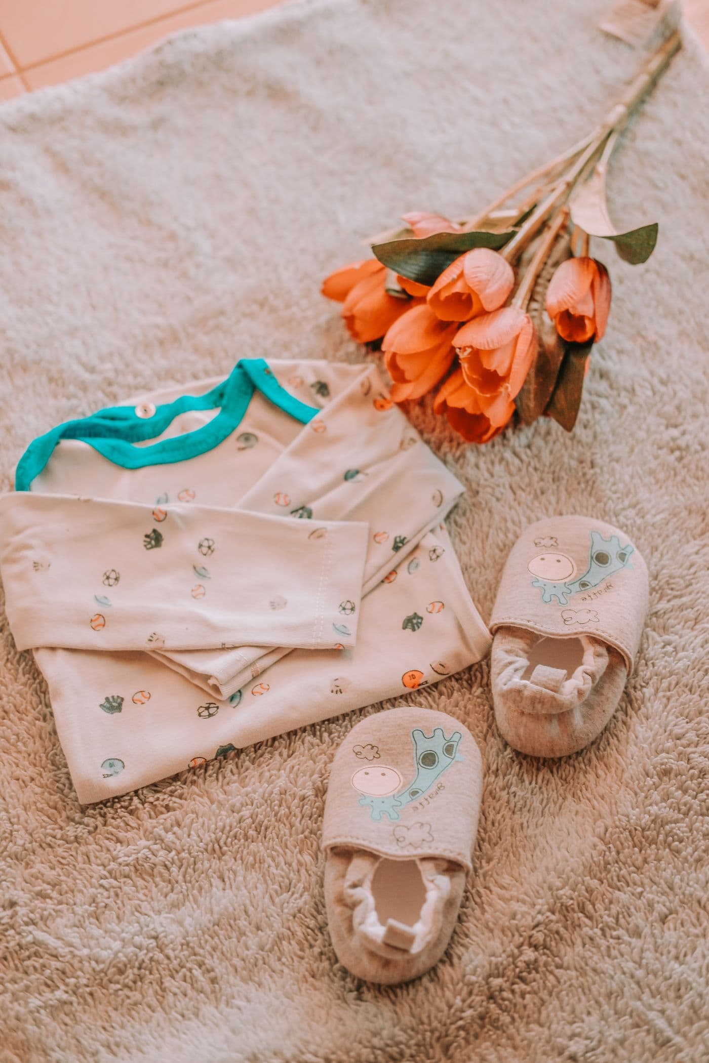 Baby clothes and booties flat lay with flowers
