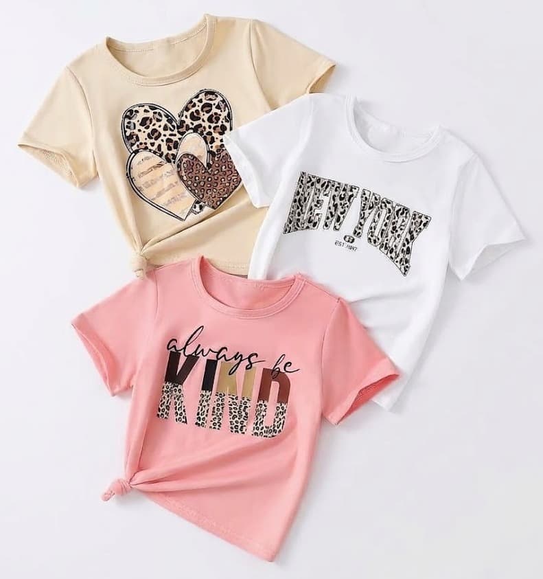 Three girls' graphic tees in beige, white and pink with leopard-print hearts