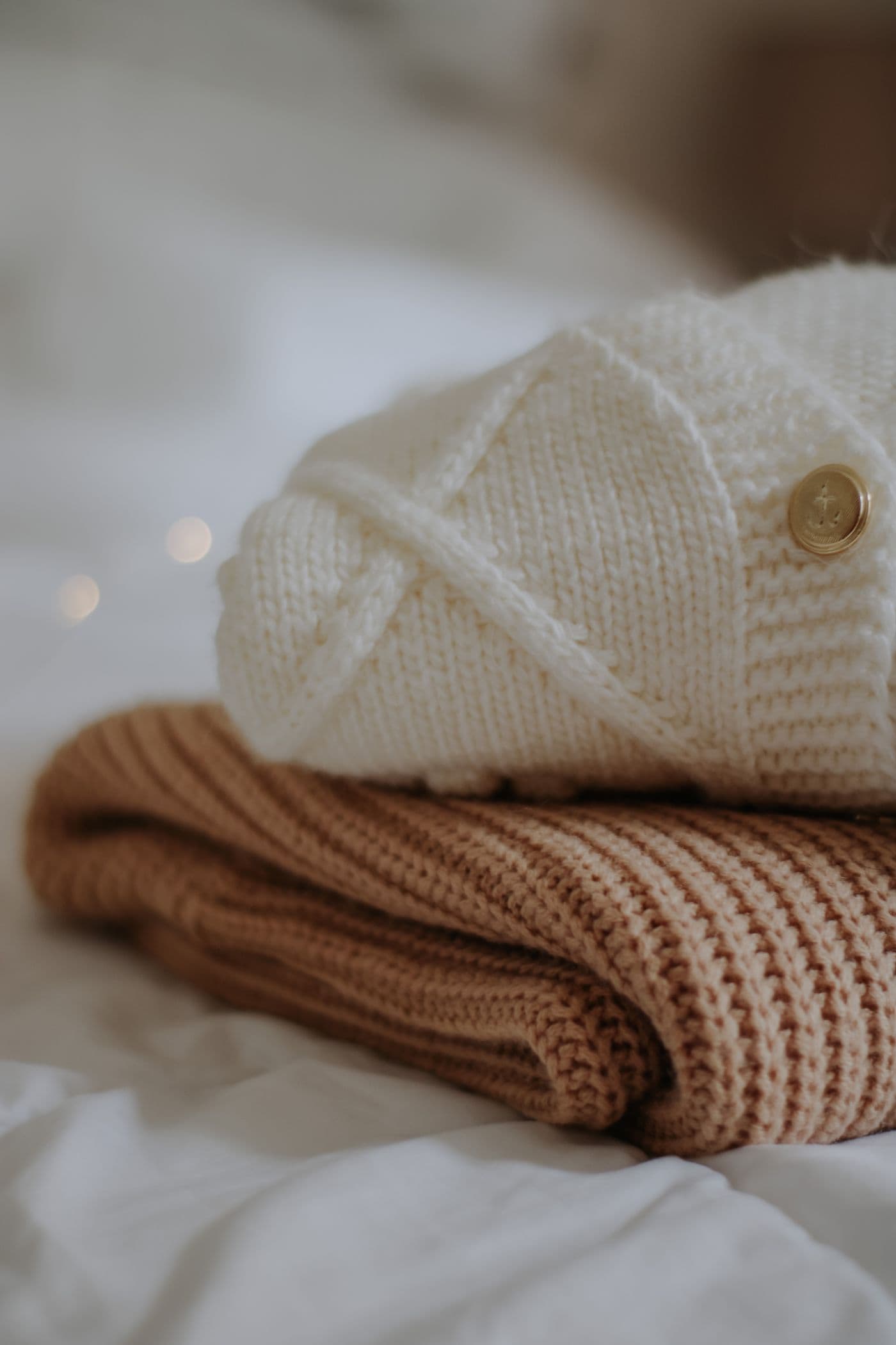 Folded knitwear stack with a cream beanie