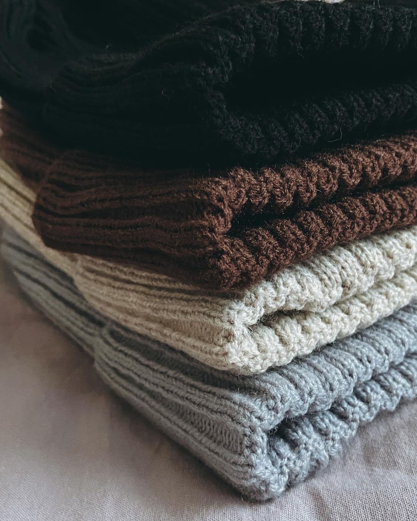 Close-up of folded knit sweaters in neutral tones