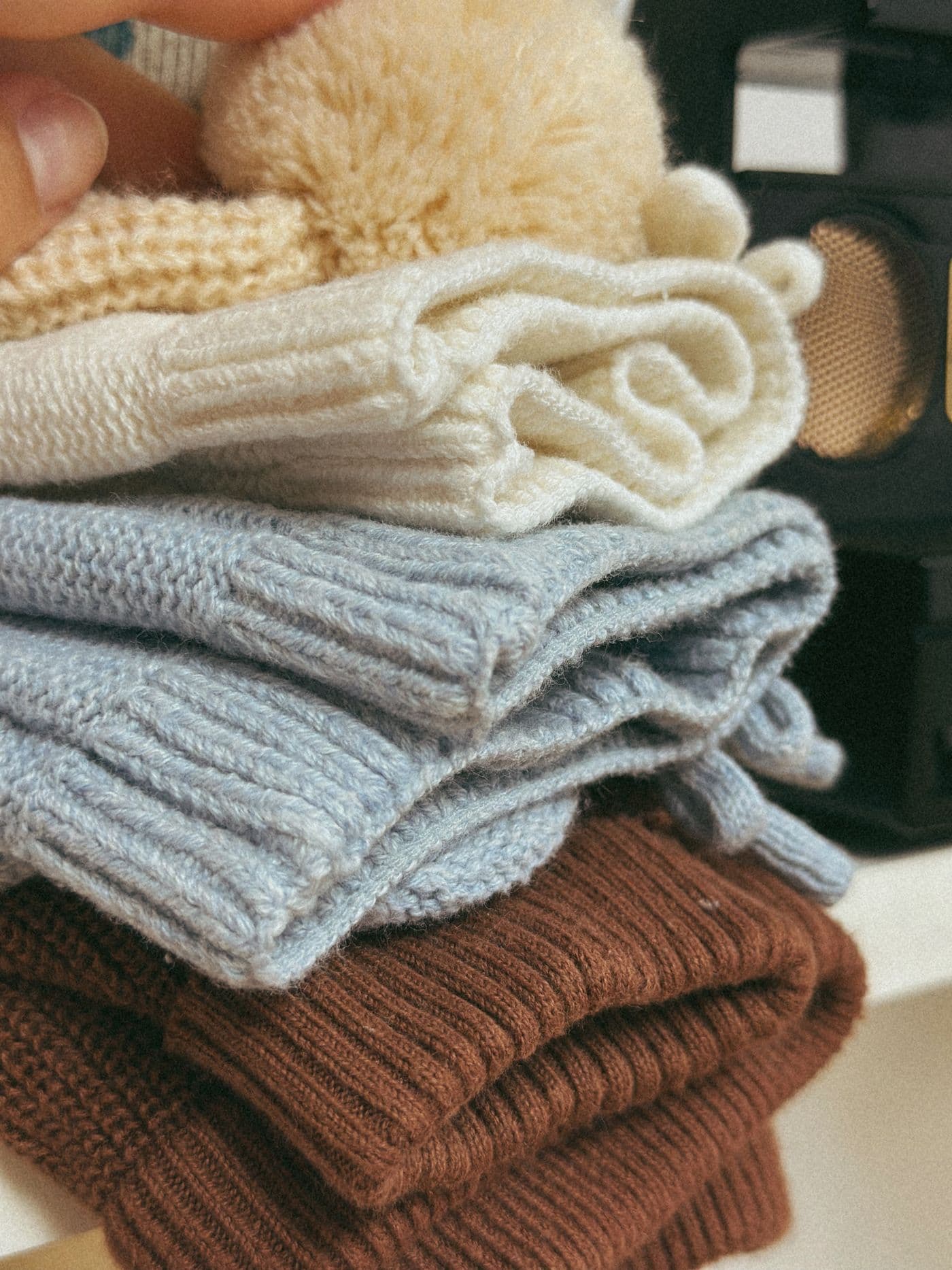 Stack of folded knit sweaters with yarn balls