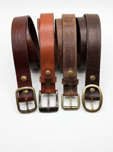 Four coiled leather belts with brass buckles in brown, tan and dark brown shades