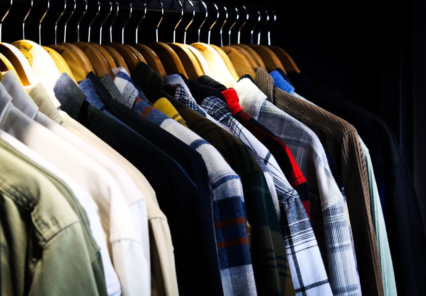Assorted men's shirts on wooden hangers